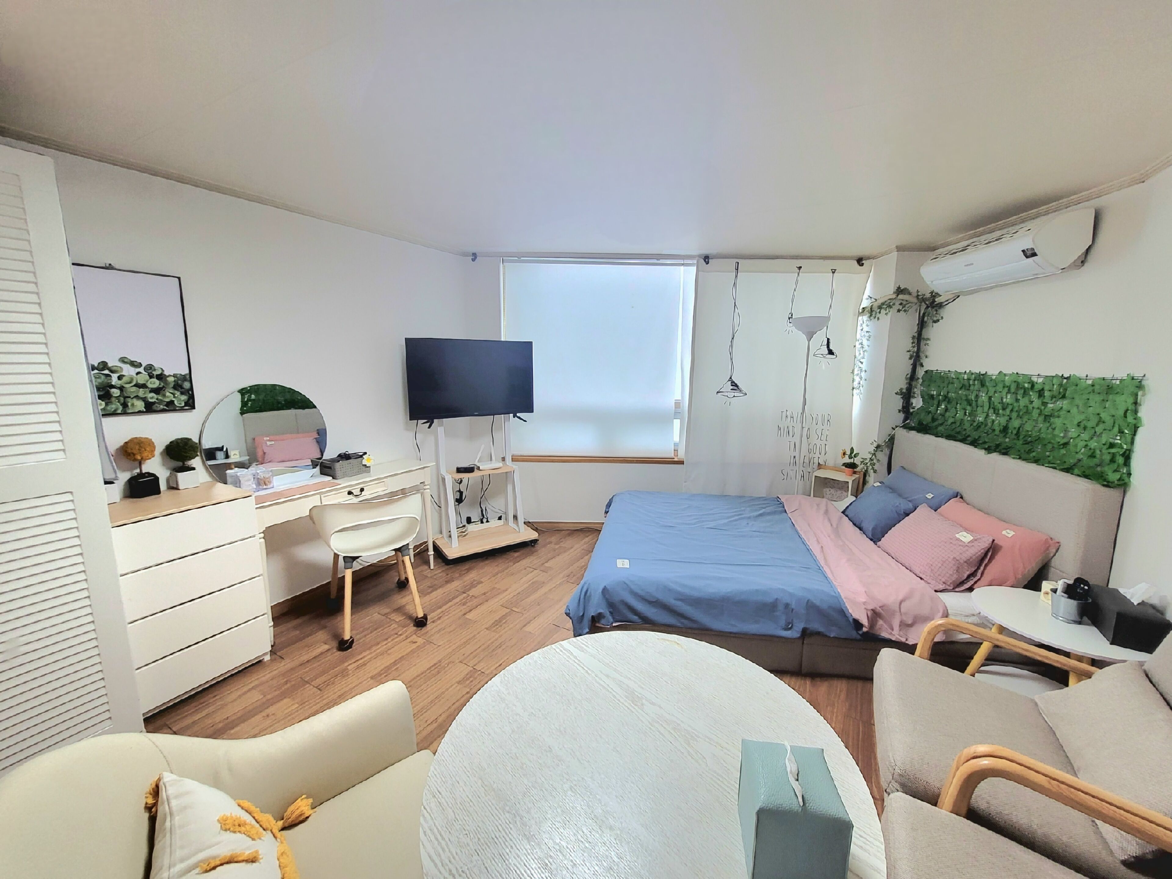 Un dormitorio con cama, escritorio, silla, televisor y ventana.