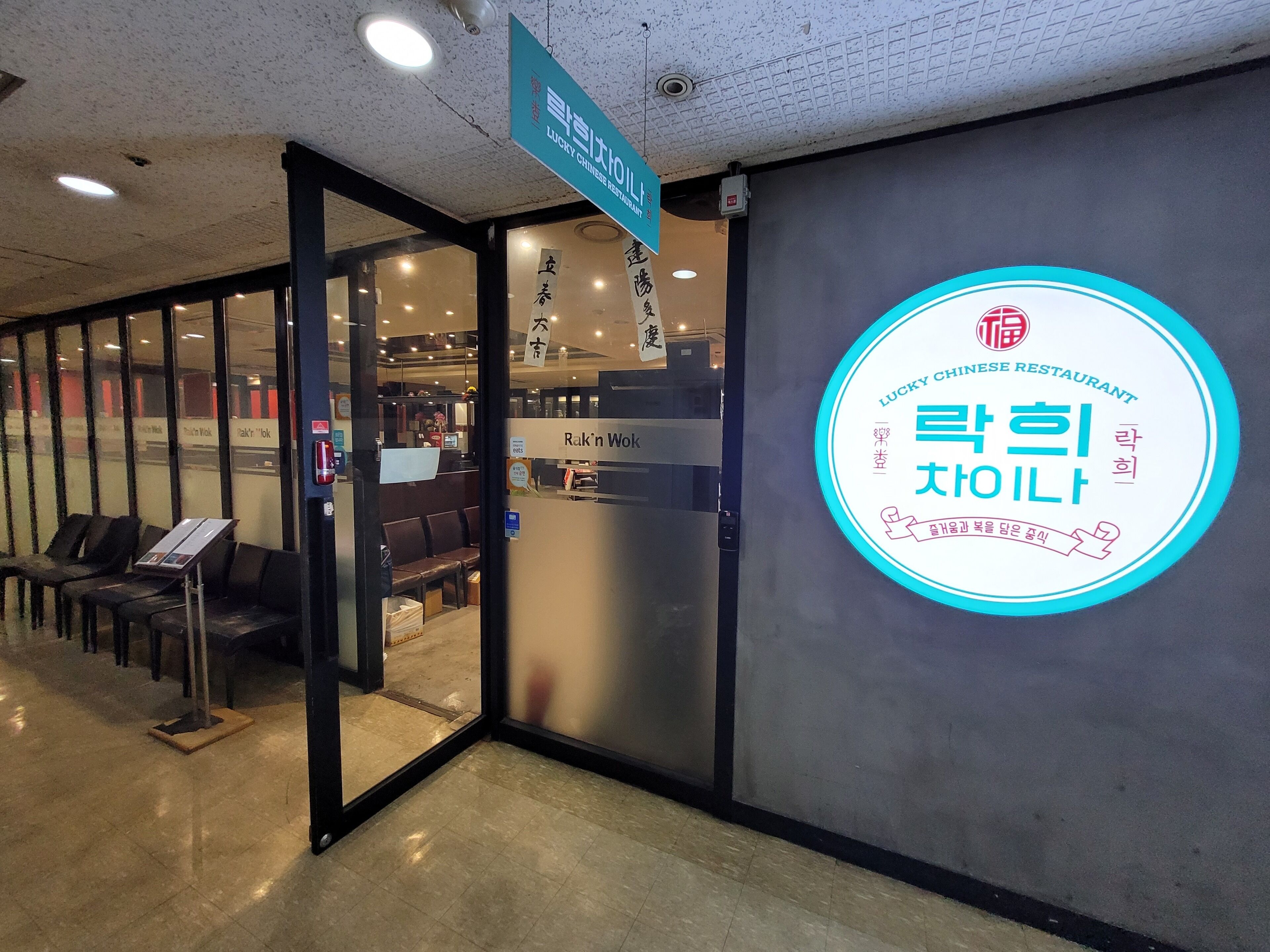 A Lucky Chinese Restaurant with a neon sign, a glass door entrance, and a seating area visible through the door.