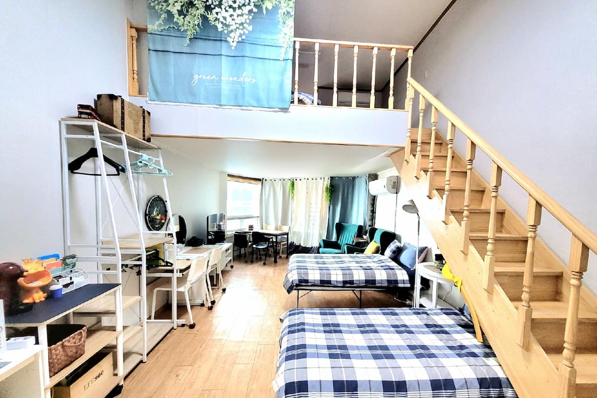 Une chambre de style « loft » avec un lit superposé, un bureau, une chaise et un escalier.