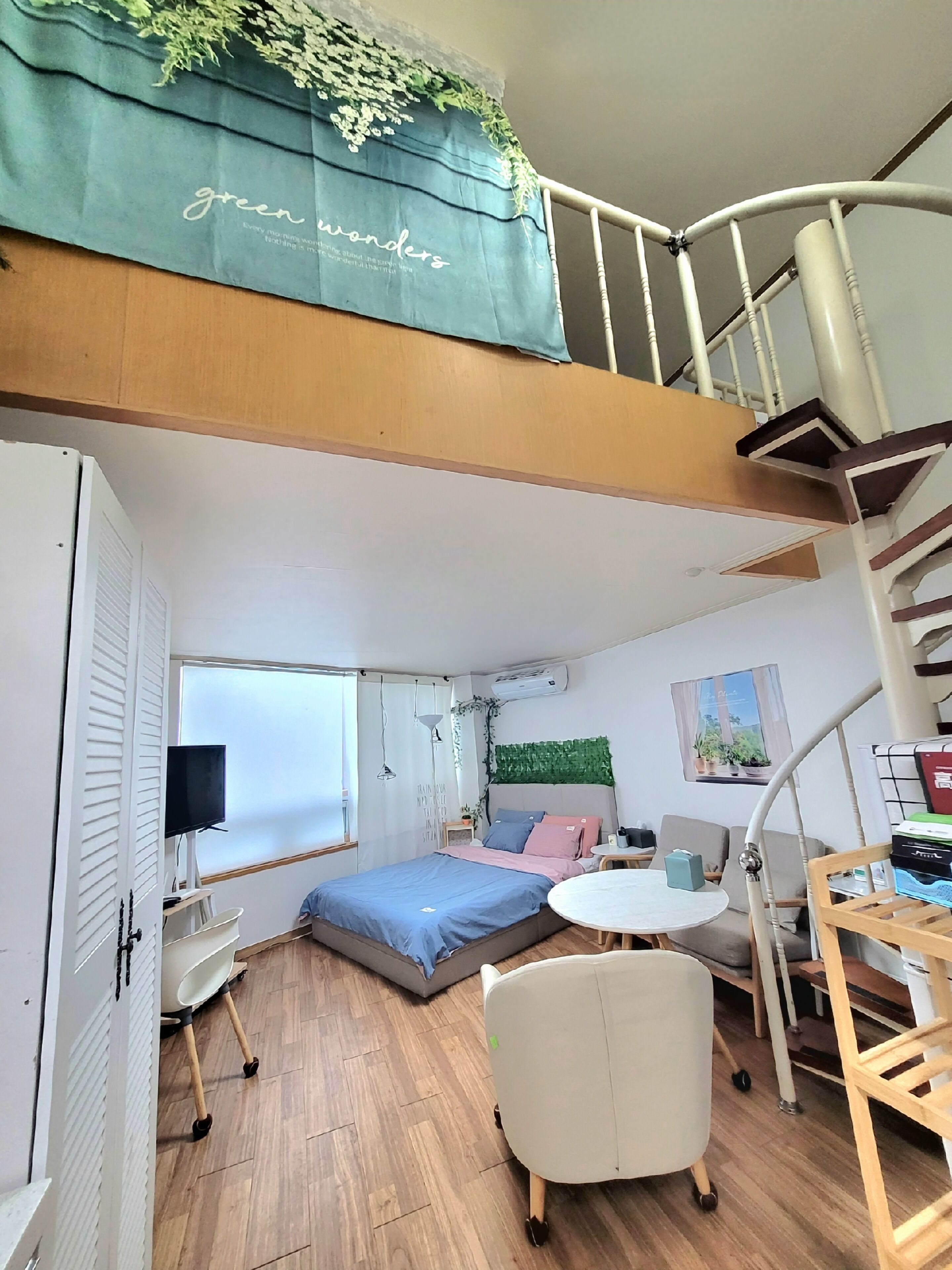 A compact room with a bunk bed, a desk, a chair, a small table, and a window.