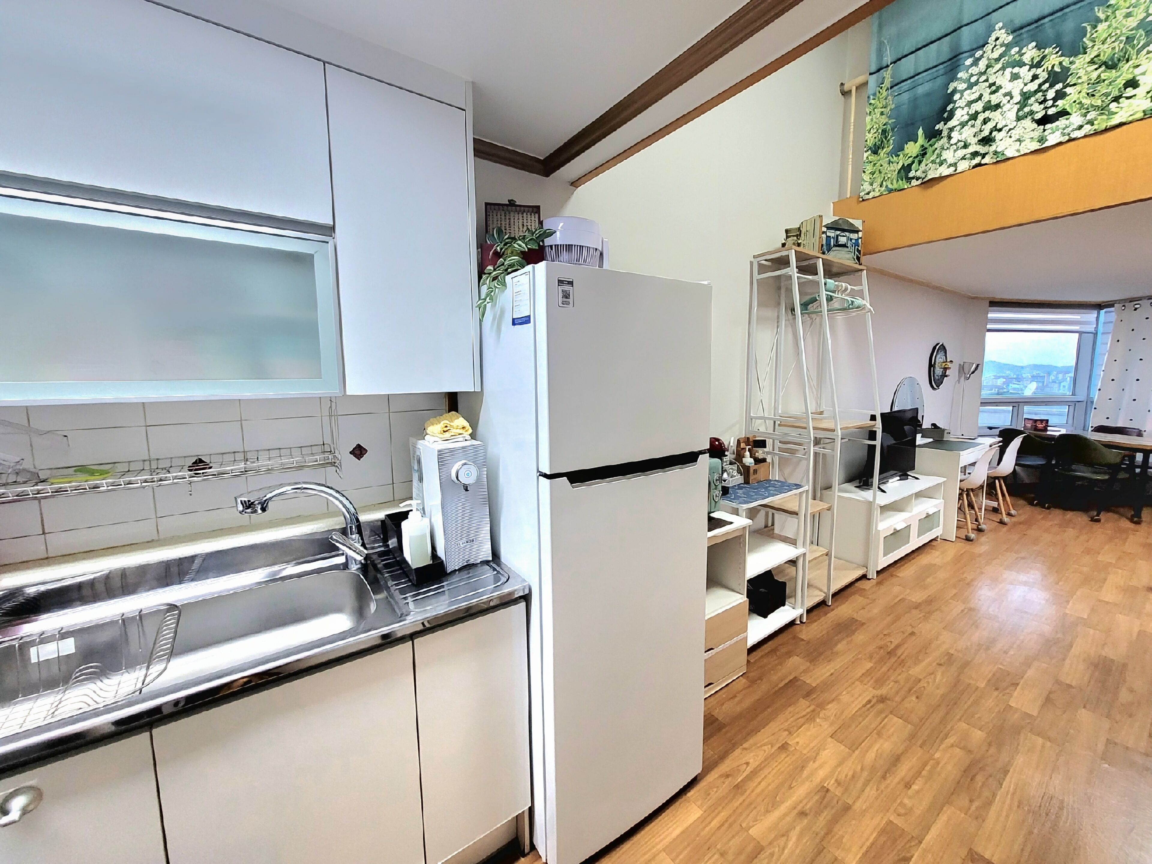 A modern kitchen with white cabinets, a stainless steel sink, and a built-in refrigerator.