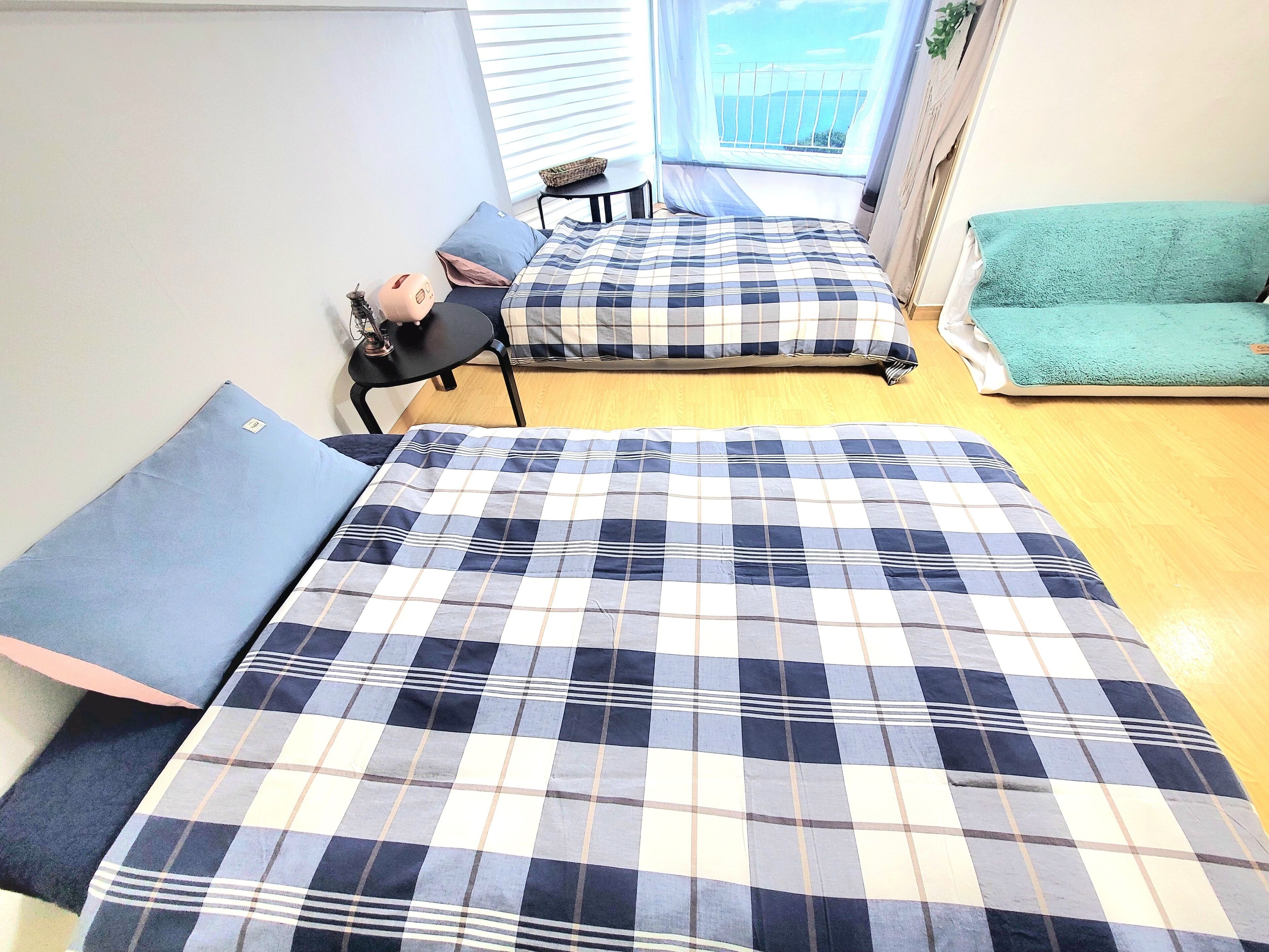 A bedroom with two beds, a small table, and a view of the sea through a window.