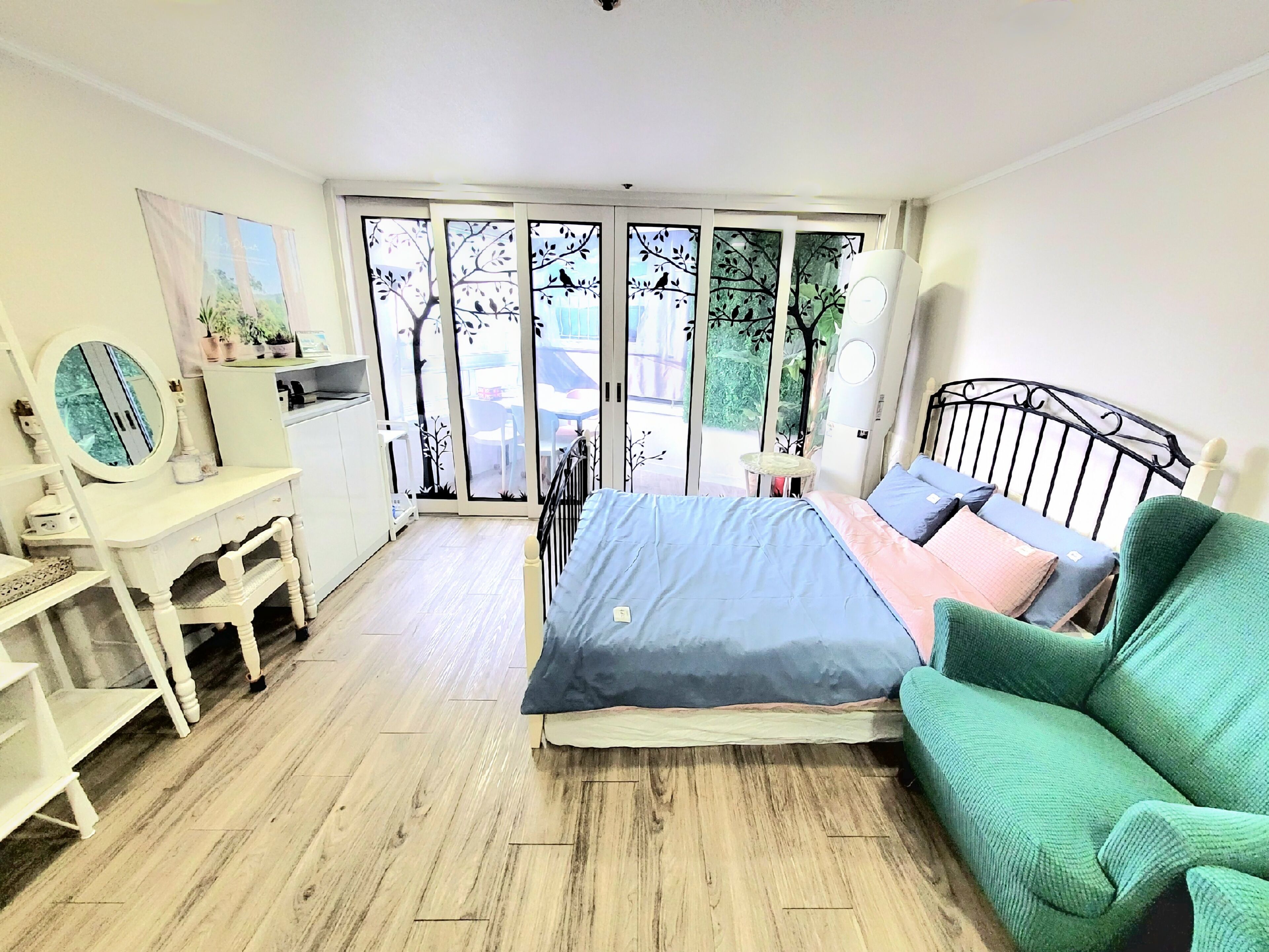 A bedroom with a bed, a desk, a chair, and a window with a view of the outdoors.