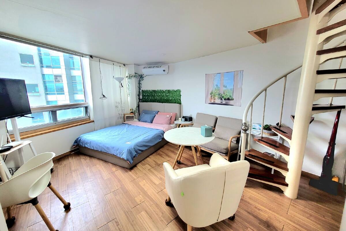 Une chambre à coucher moderne comprenant un lit, un bureau, une chaise, une petite table, un canapé et un escalier.