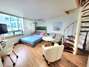 Een moderne slaapkamer met een bed, een bureau, een stoel, een klein tafeltje, een bank en een trap.