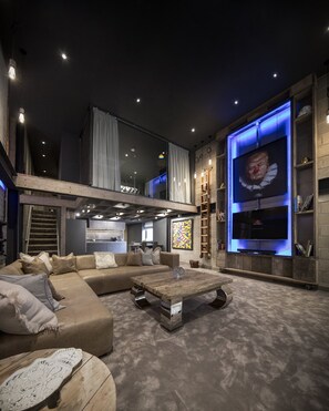 A modern living room with a large sectional sofa, a wooden coffee table, and a flat-screen TV mounted on a wall. - The Bells (Leeds)