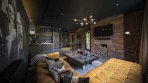 A modern living room with a leather sofa, a coffee table, and a fireplace. - The Bells (Leeds)