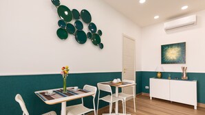 A dining area with a table, chairs, and a wall-mounted decorative piece. - Napolilive (Naples)