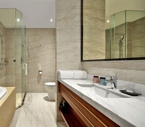 Un baño moderno con cabina de ducha de vidrio, inodoro y tocador con un espejo grande.
