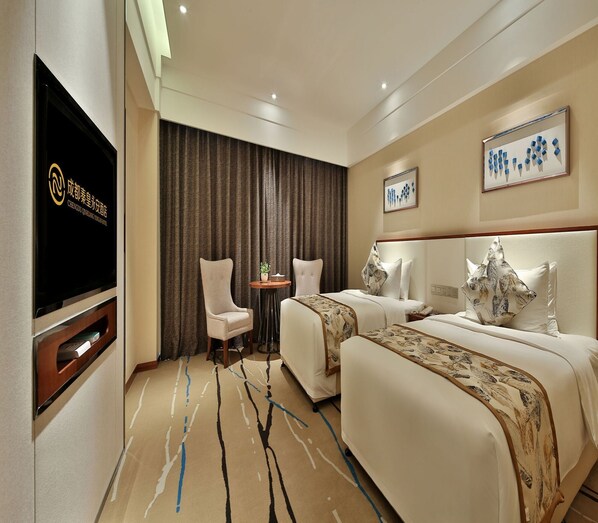 Habitación de hotel con dos camas, televisión, una mesita y una silla.