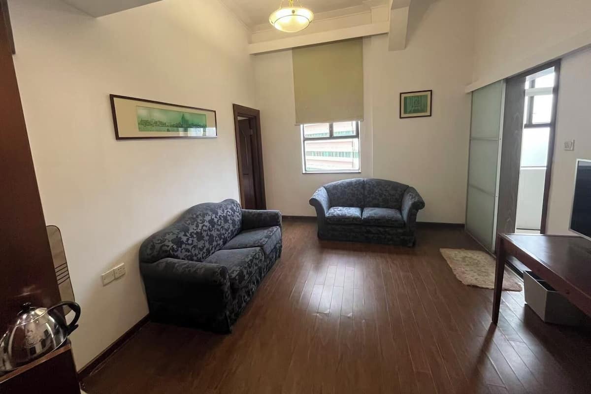 A living room with two sofas, a TV stand, a window, and a ceiling light.