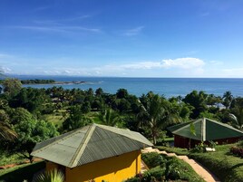 Un resort tropical con vista al océano, rodeado de exuberante vegetación y palmeras.