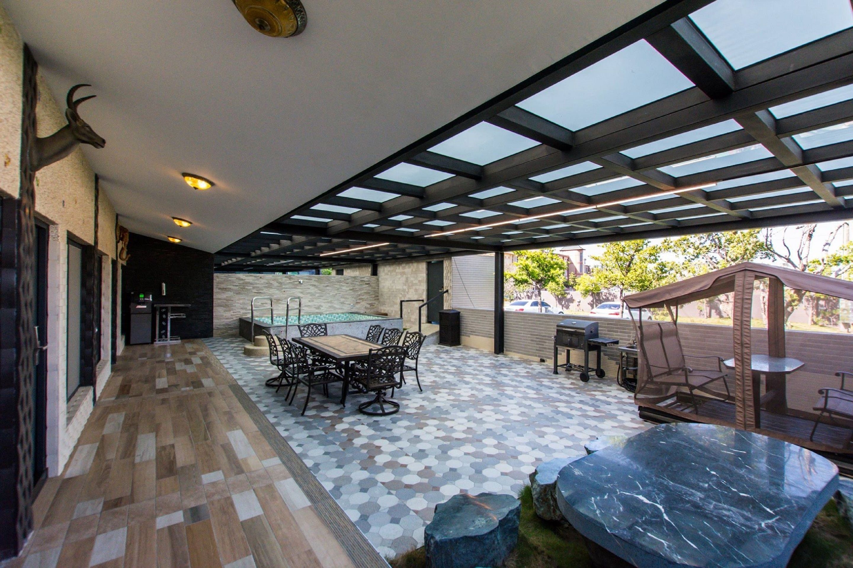 An outdoor patio with a pool, a dining area, and a seating area with a canopy.