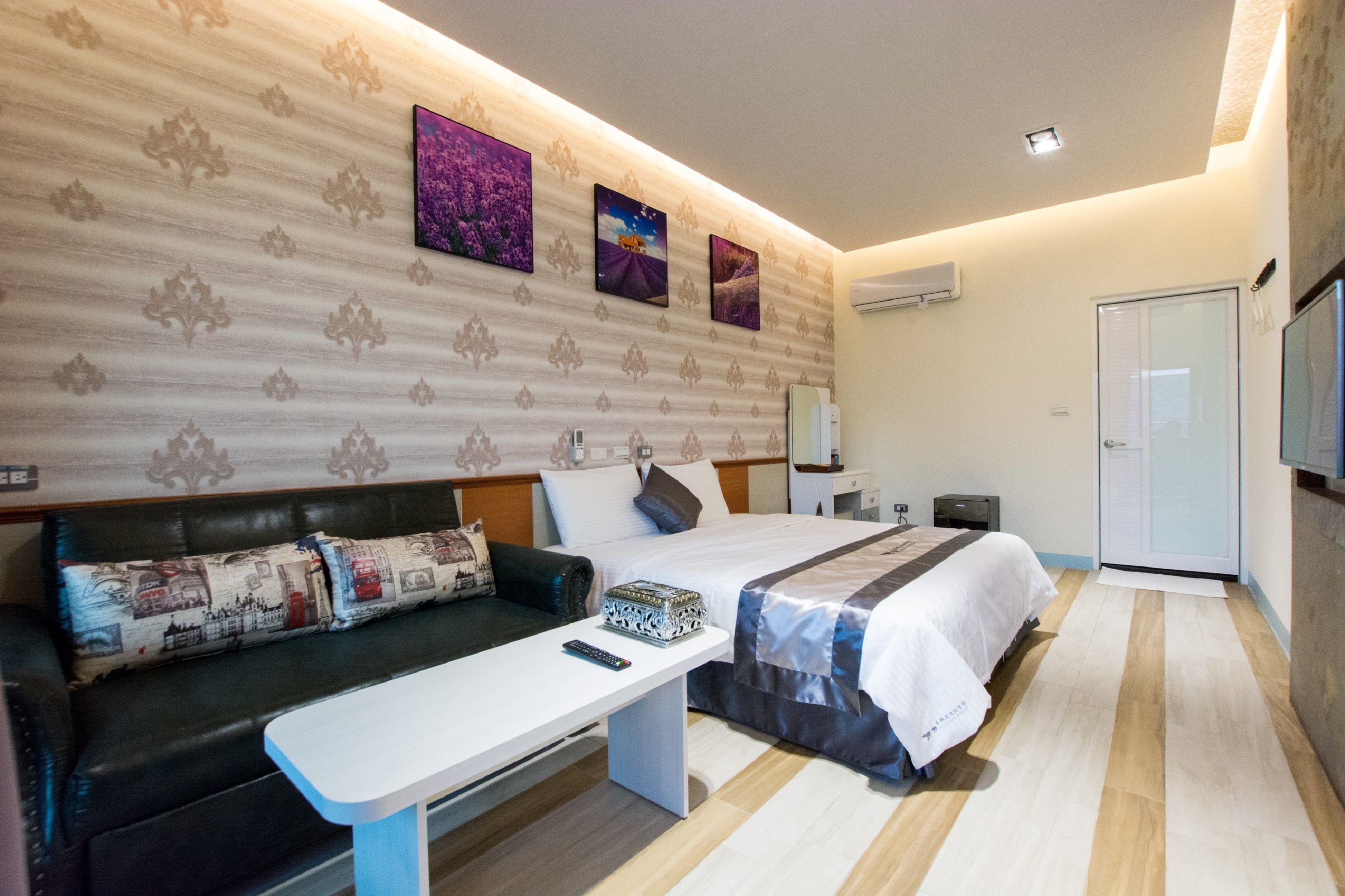 Een hotelkamer met een bed, een slaapbank, een nachtkastje en een televisie.