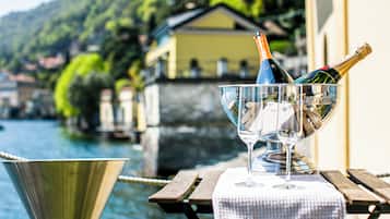 A table with a bottle of champagne and a glass on a wooden table by a body of water.