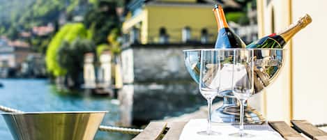 Una mesa con una botella de champán y una copa junto al agua.