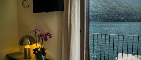 Una habitación con televisión montada en la pared, una lámpara y una orquídea en maceta.