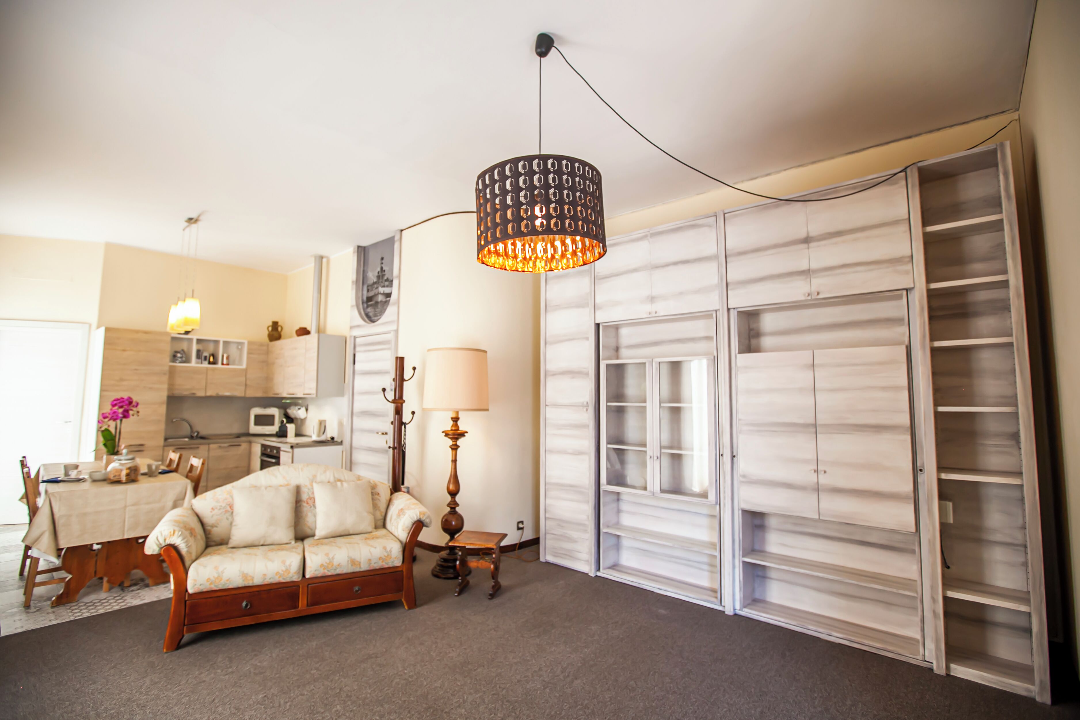 A living room with a sofa, a table, a lamp, and a wardrobe.