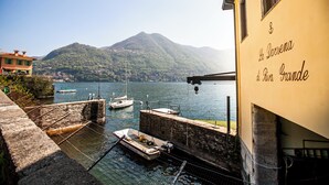Un edificio frente al agua con un letrero que dice “La Darsena al Torrione Grande”. Hay barcos amarrados en el agua y una montaña se divisa al fondo.