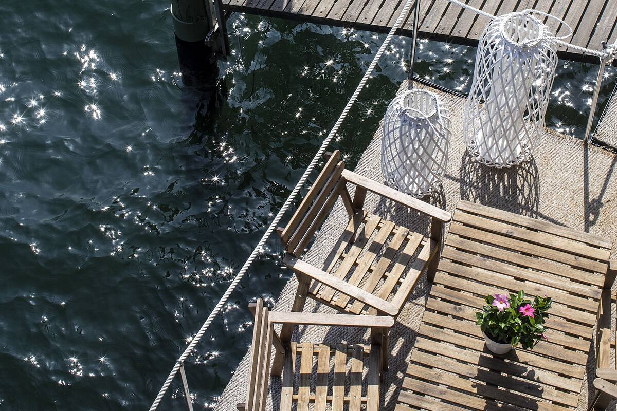 A wooden deck with metal chairs and a table, overlooking a body of water.