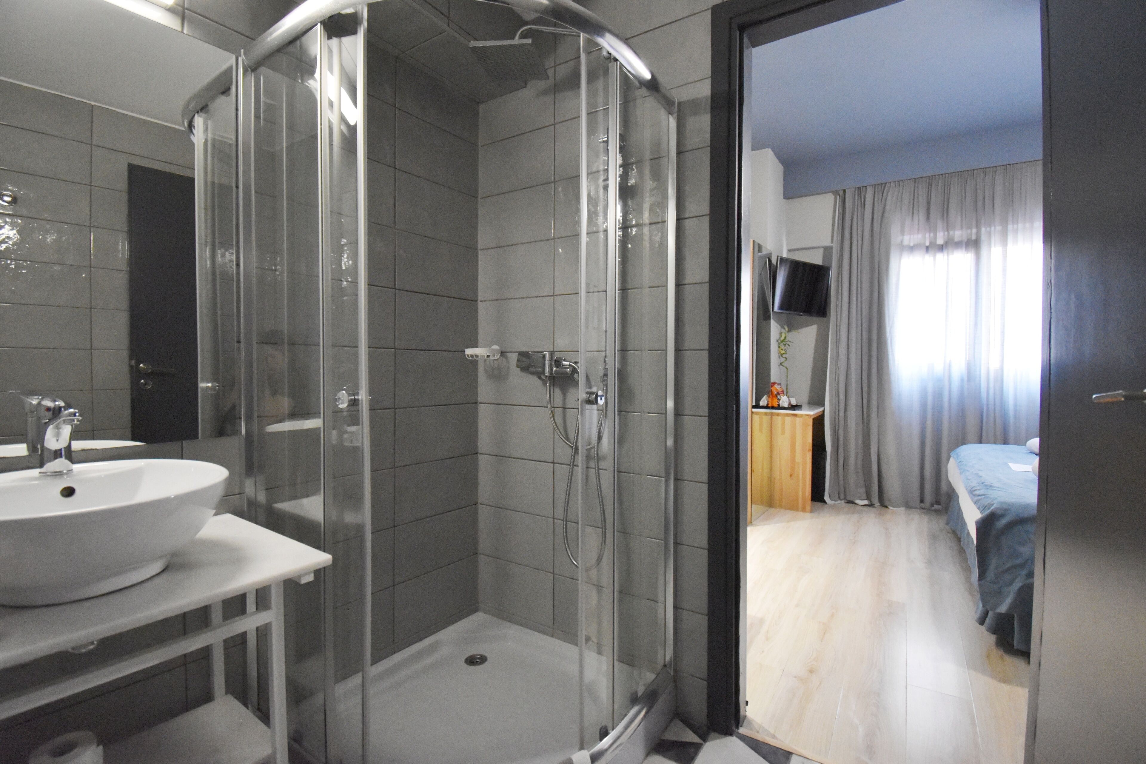 A modern bathroom with a glass-enclosed shower, a white sink, and a mirror.