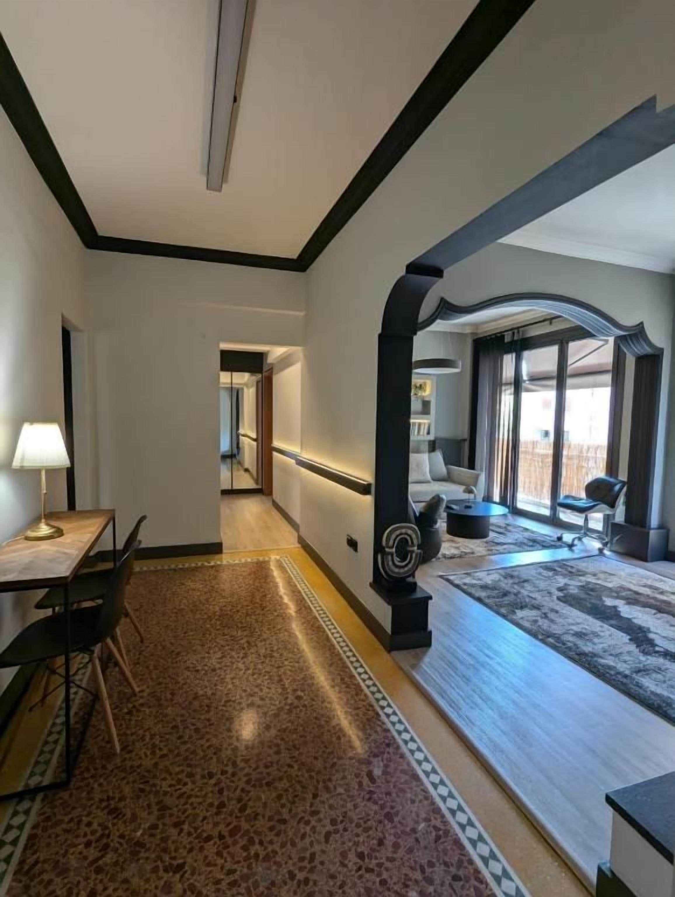 A modern hotel room with a dining area, a large window, and a decorative column.