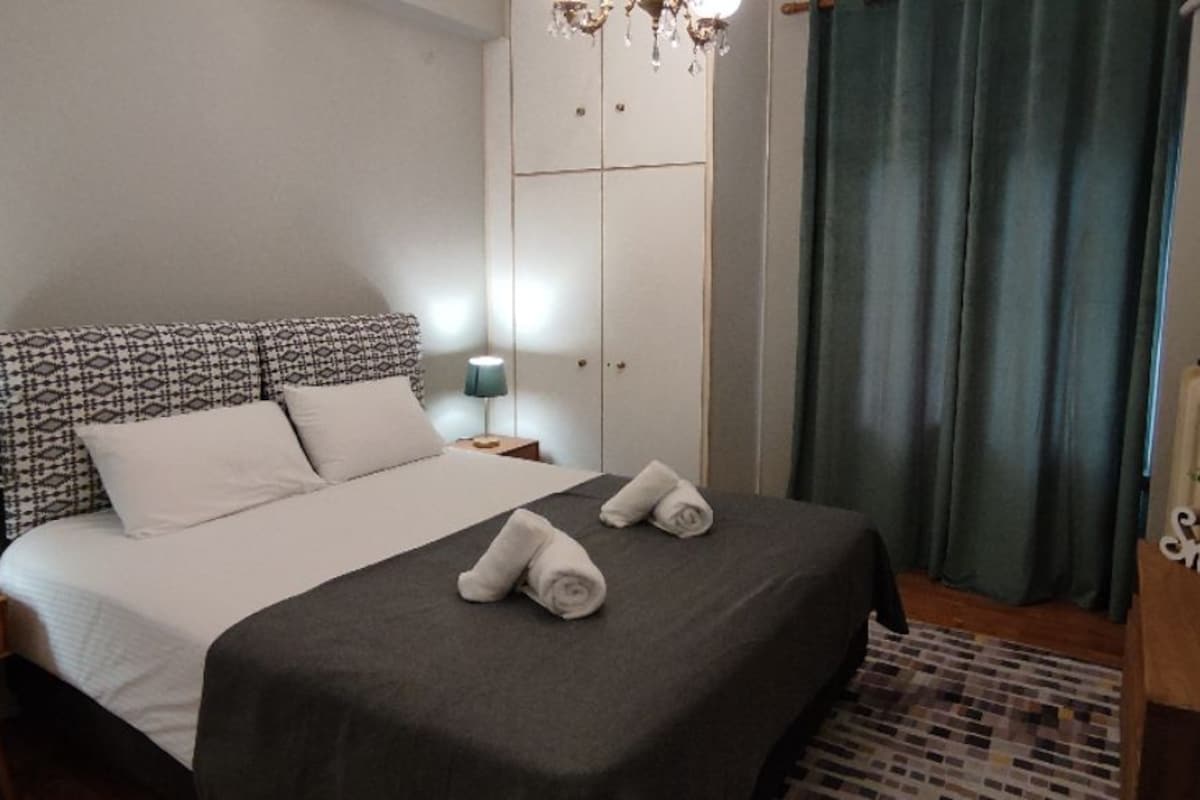 Un dormitorio ordenado con cama, mesitas de noche, armario y candelabro.