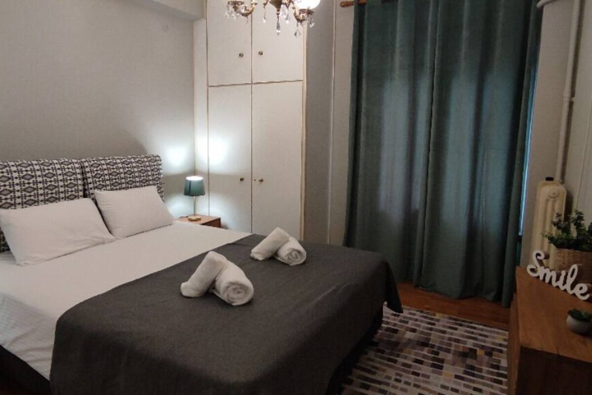 A neatly arranged bedroom with a bed, bedside tables, a wardrobe, and a chandelier.