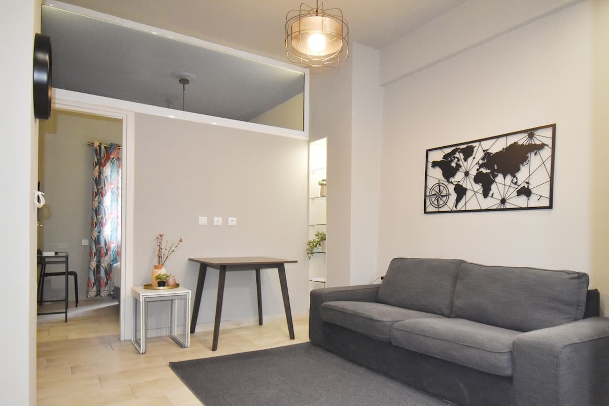 A modern living room with a grey sofa, a small side table, a world map artwork, and a wooden floor.