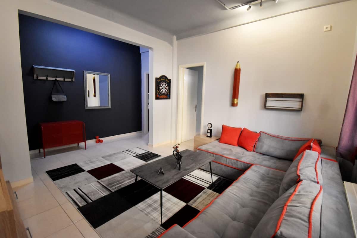 A modern living room with a sectional sofa, a coffee table, a red bench, and a variety of rugs.