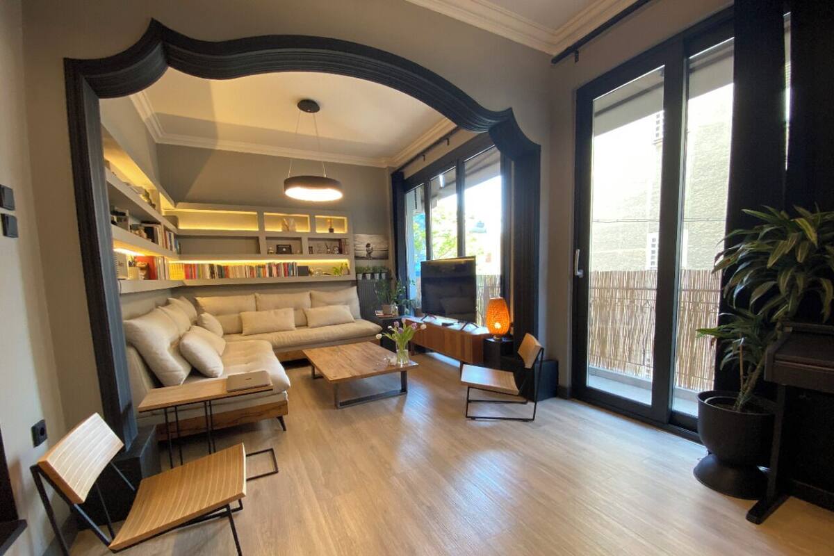 A spacious living room with a sofa, coffee table, and chairs, a fireplace, and a bookshelf.