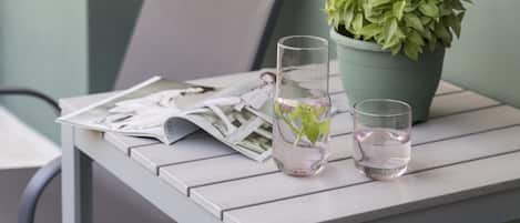 Ein Tisch mit einem Blumentopf, zwei Gläsern Wasser und ein paar Zeitungen.