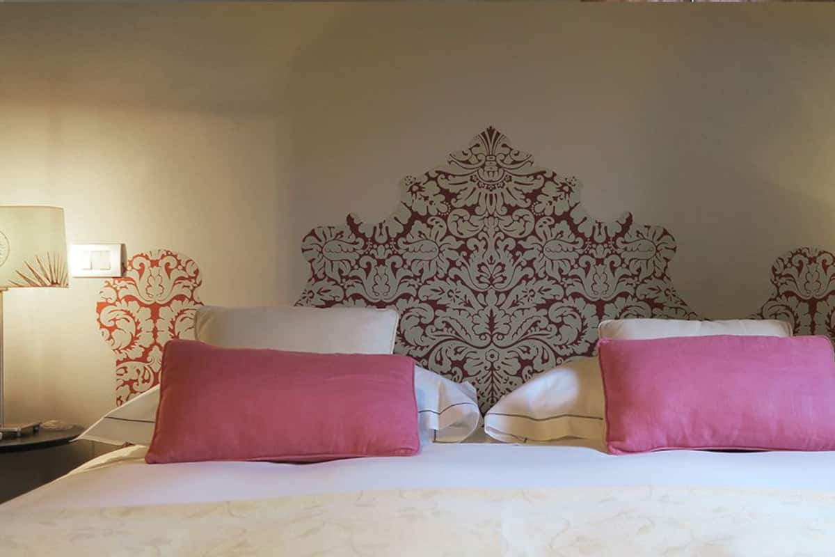 A neatly made bed with a patterned headboard, two bedside lamps, and a wall-mounted decorative piece.