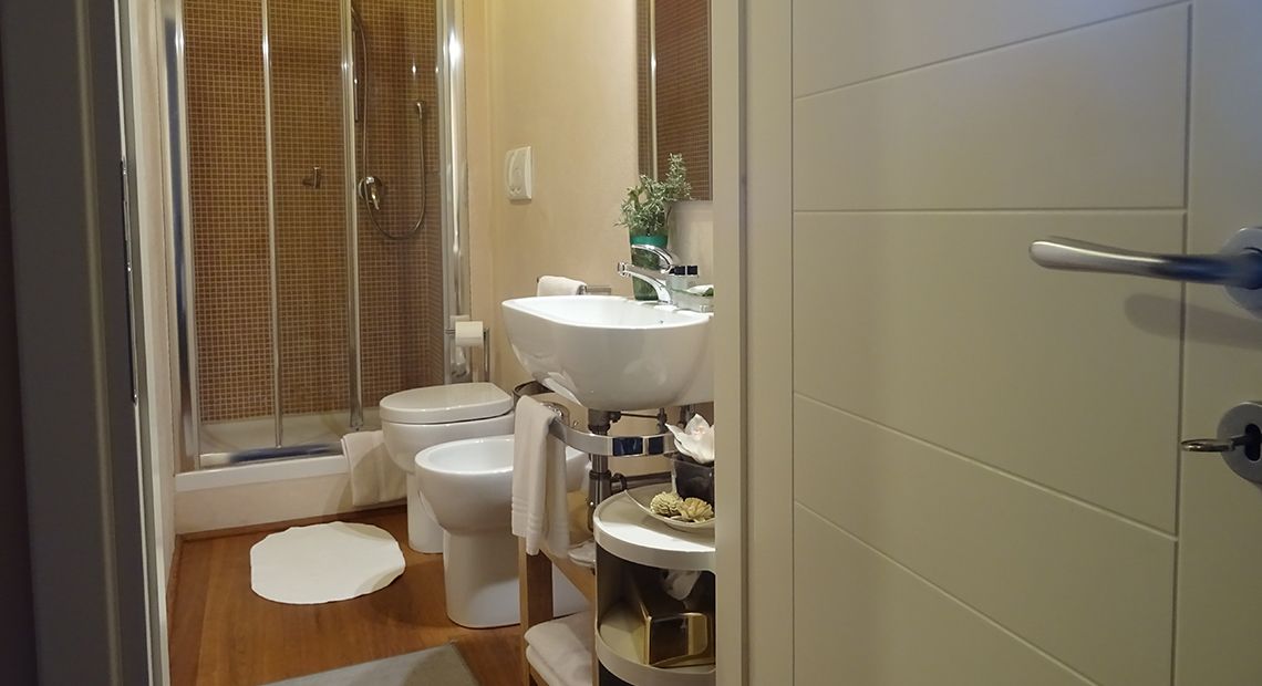 A bathroom with a shower, toilet, sink, and a small shelf with toiletries.