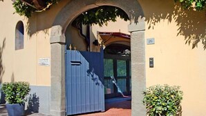 A building with a stone archway entrance, a blue gate, and potted plants. - Duchess Boutique Hotel B&B (Florence)