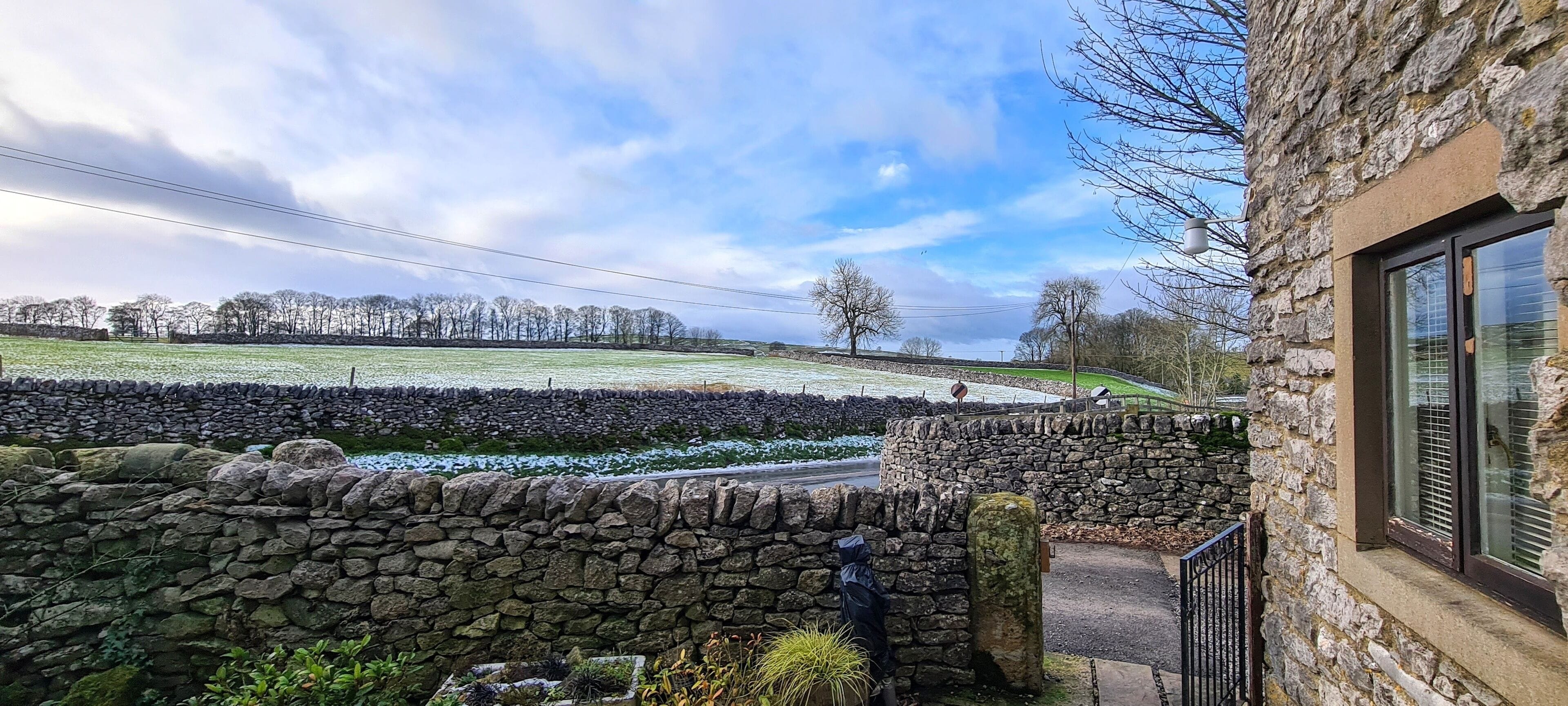 A stone wall with a stone pathway leading to a building with a window.
