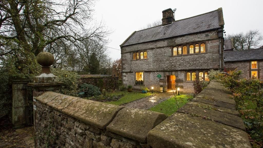 A stone house with multiple windows and a well-lit entrance.