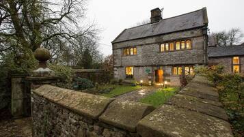 A stone house with multiple windows and a well-lit entrance.