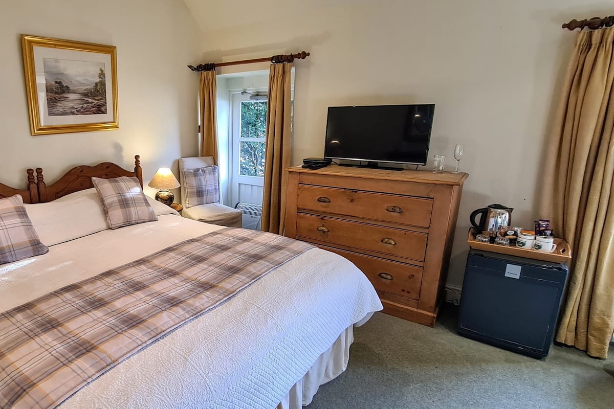 A bedroom with a bed, a dresser, a television, and a small refrigerator.