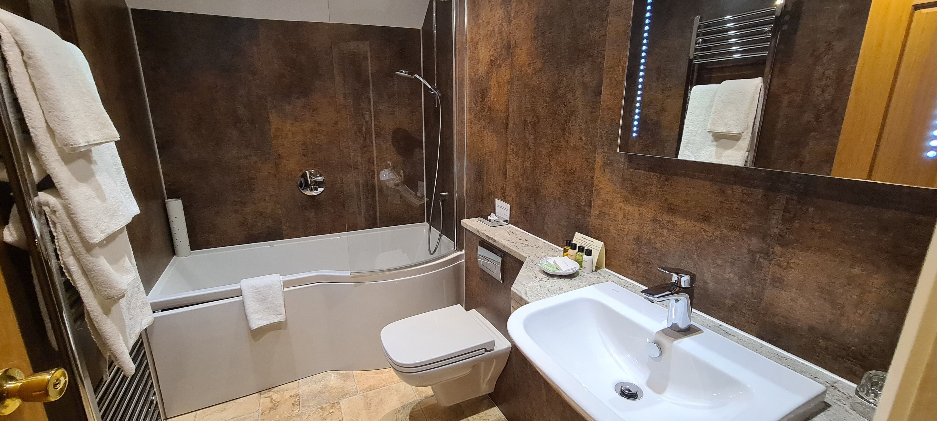 A bathroom with a bathtub, toilet, sink, and a shower area.