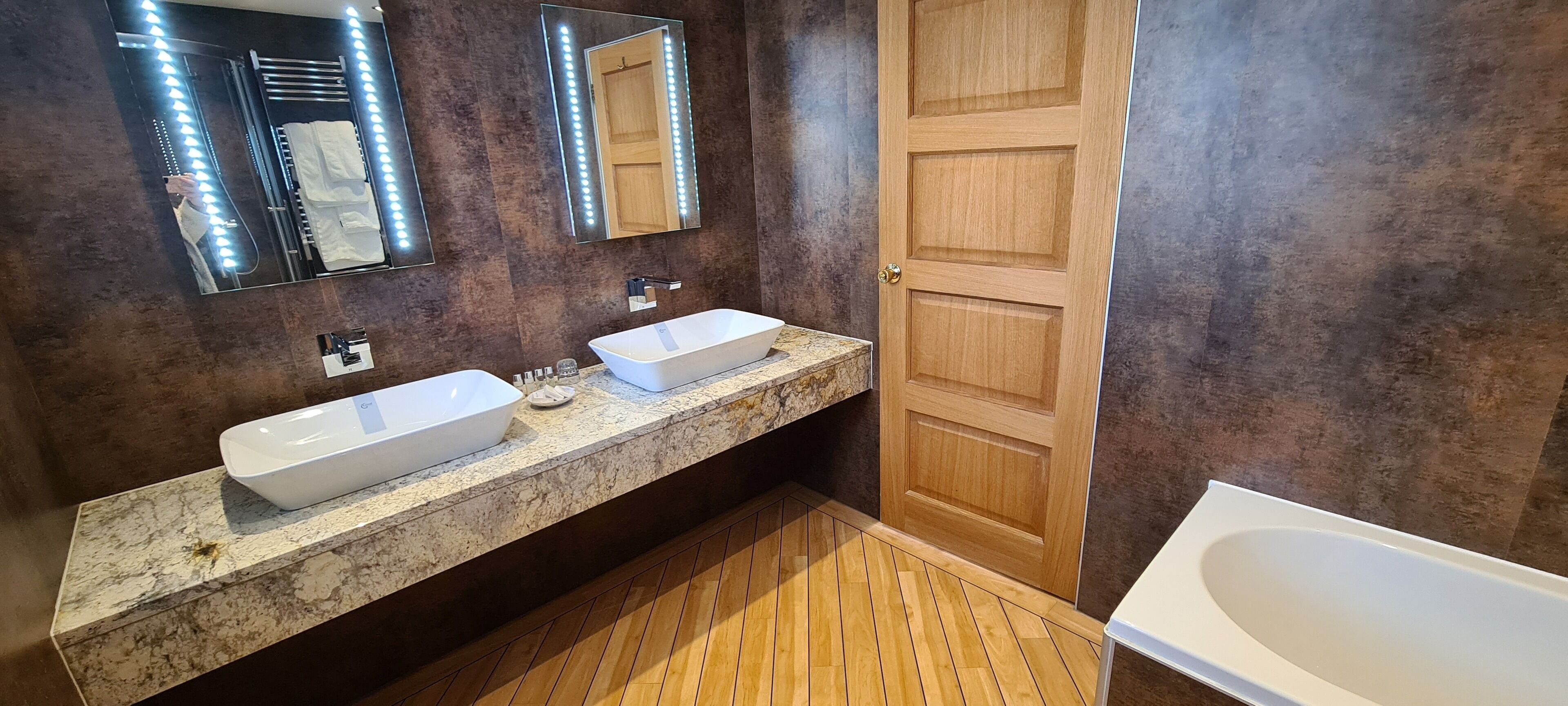 A bathroom with two sinks, a large mirror, and a wooden door.