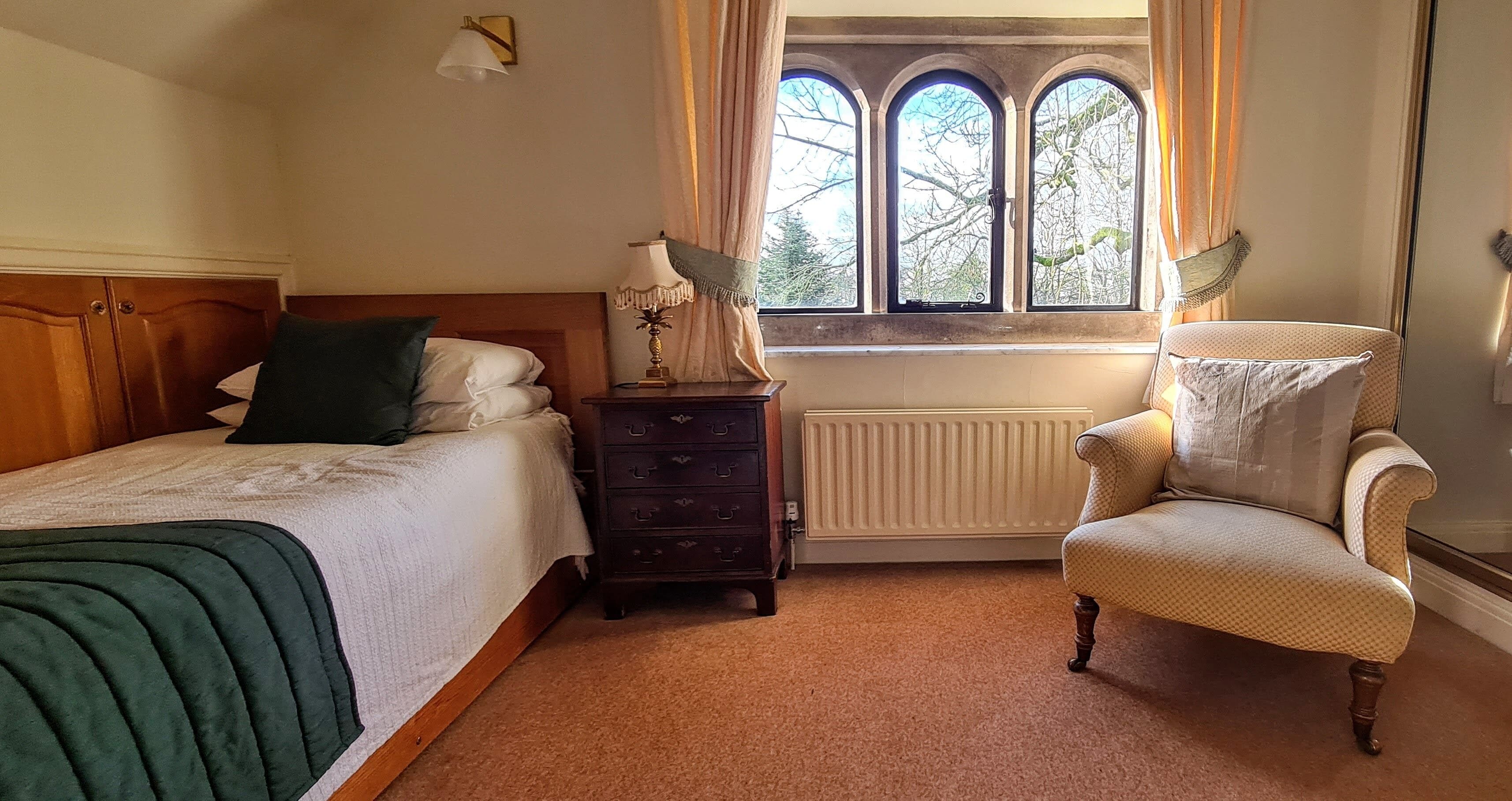 A bedroom with a bed, a dresser, a chair, and a window with curtains.