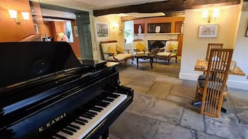 A grand piano in a well-lit room with stone flooring, a fireplace, and comfortable seating.