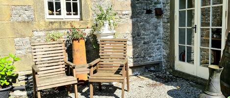 A stone building with a wooden bench and potted plants.