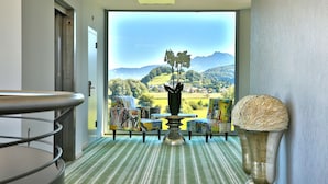 A room with a view of a mountainous landscape, a dining area with a table and chairs, and a decorative vase. - Hotel Rhy (Oberriet)