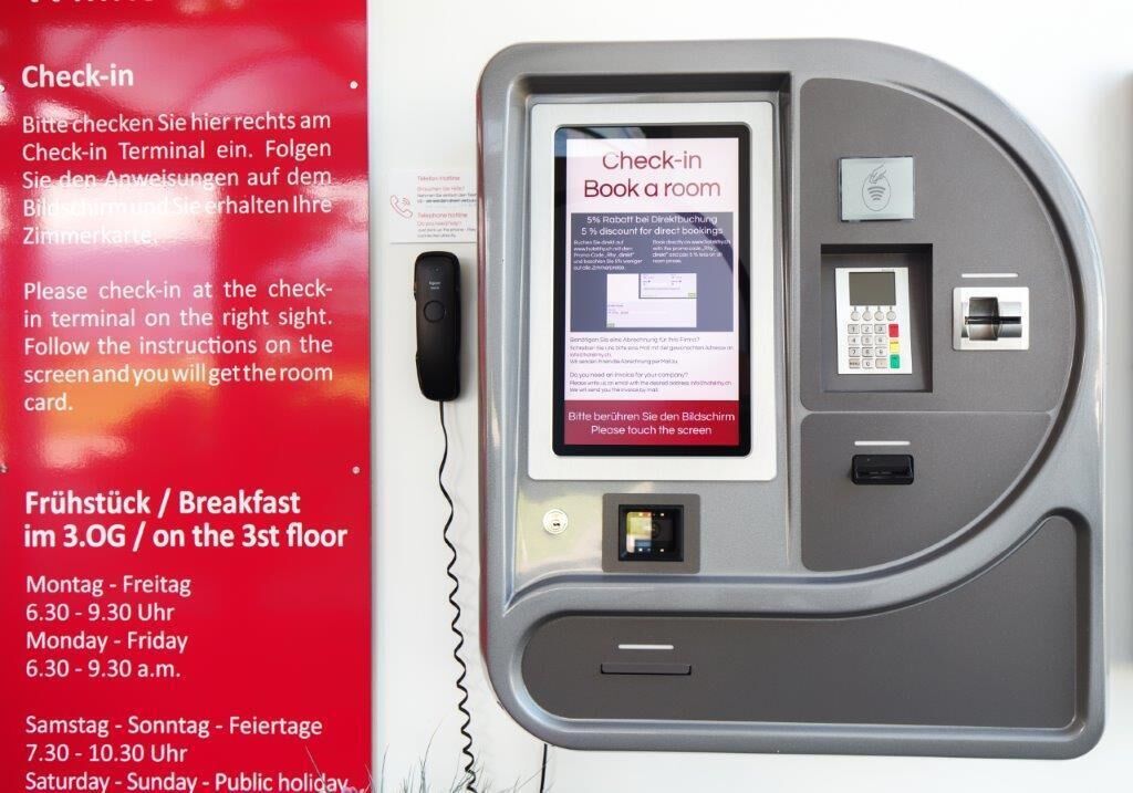 A check-in kiosk with a screen displaying instructions for booking a room.
