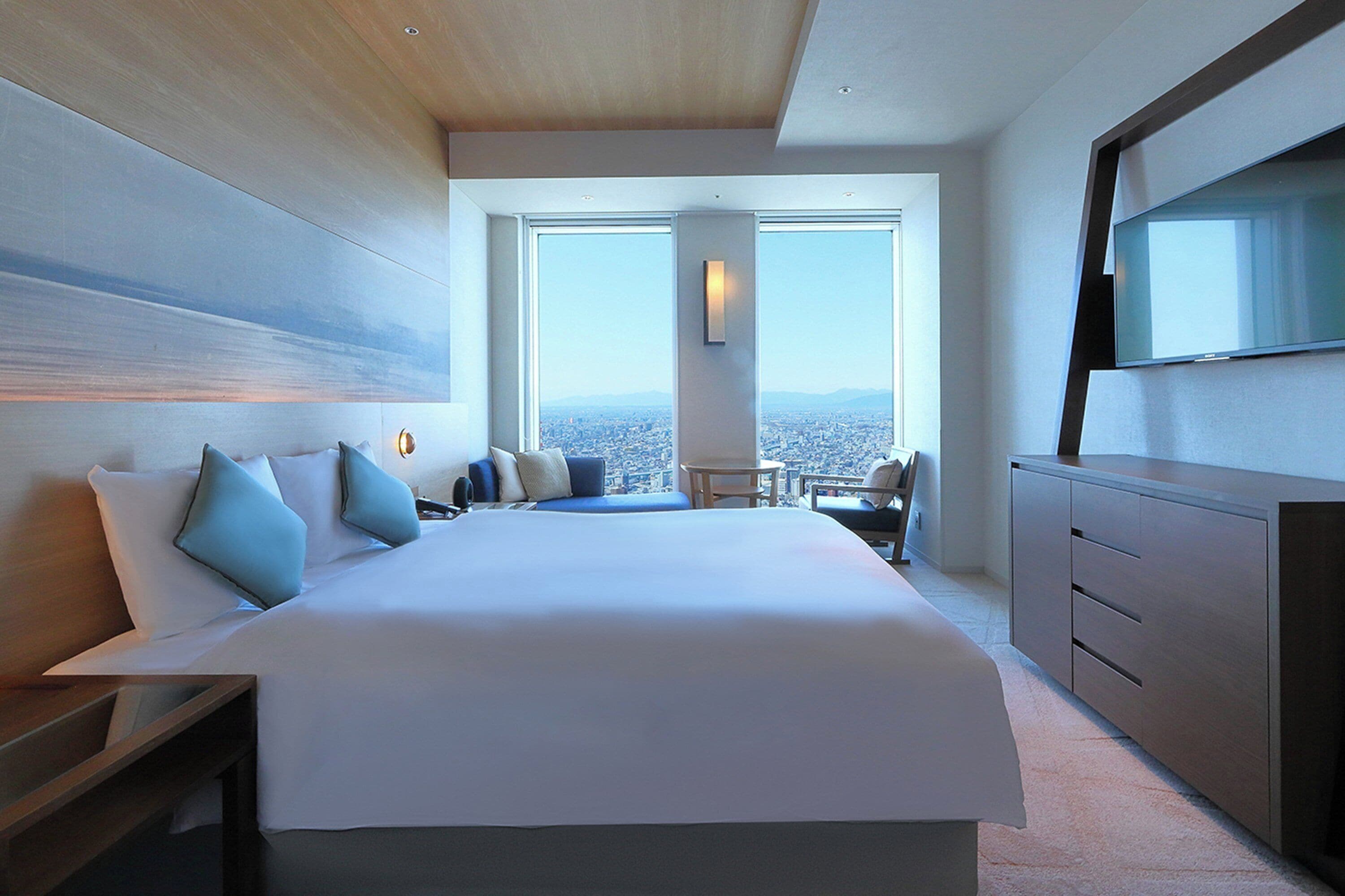 Una habitación de hotel moderna con una cama grande, un escritorio, una silla y un televisor.