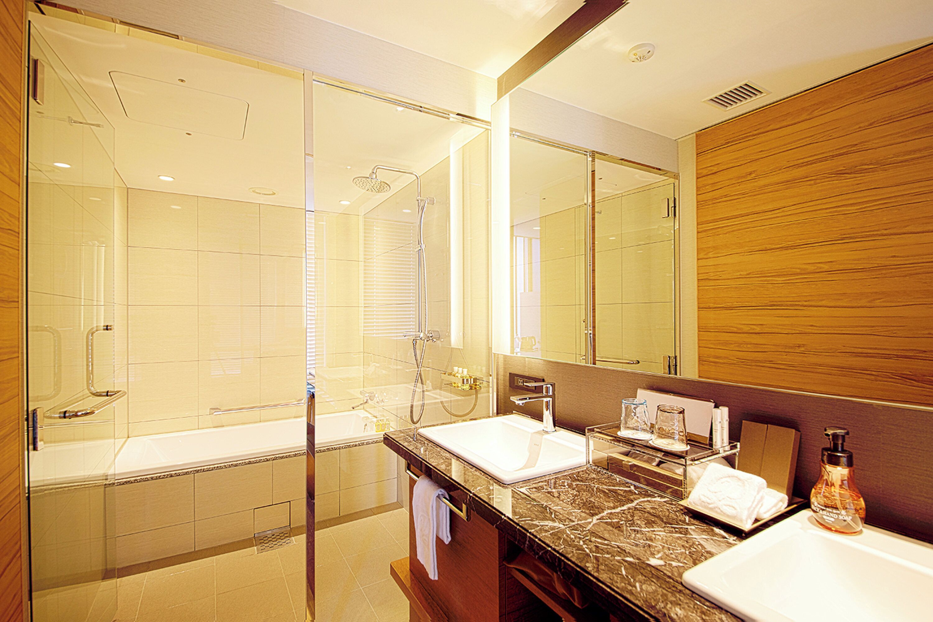 A modern bathroom with a glass-enclosed shower, a double sink vanity, and a large mirror.