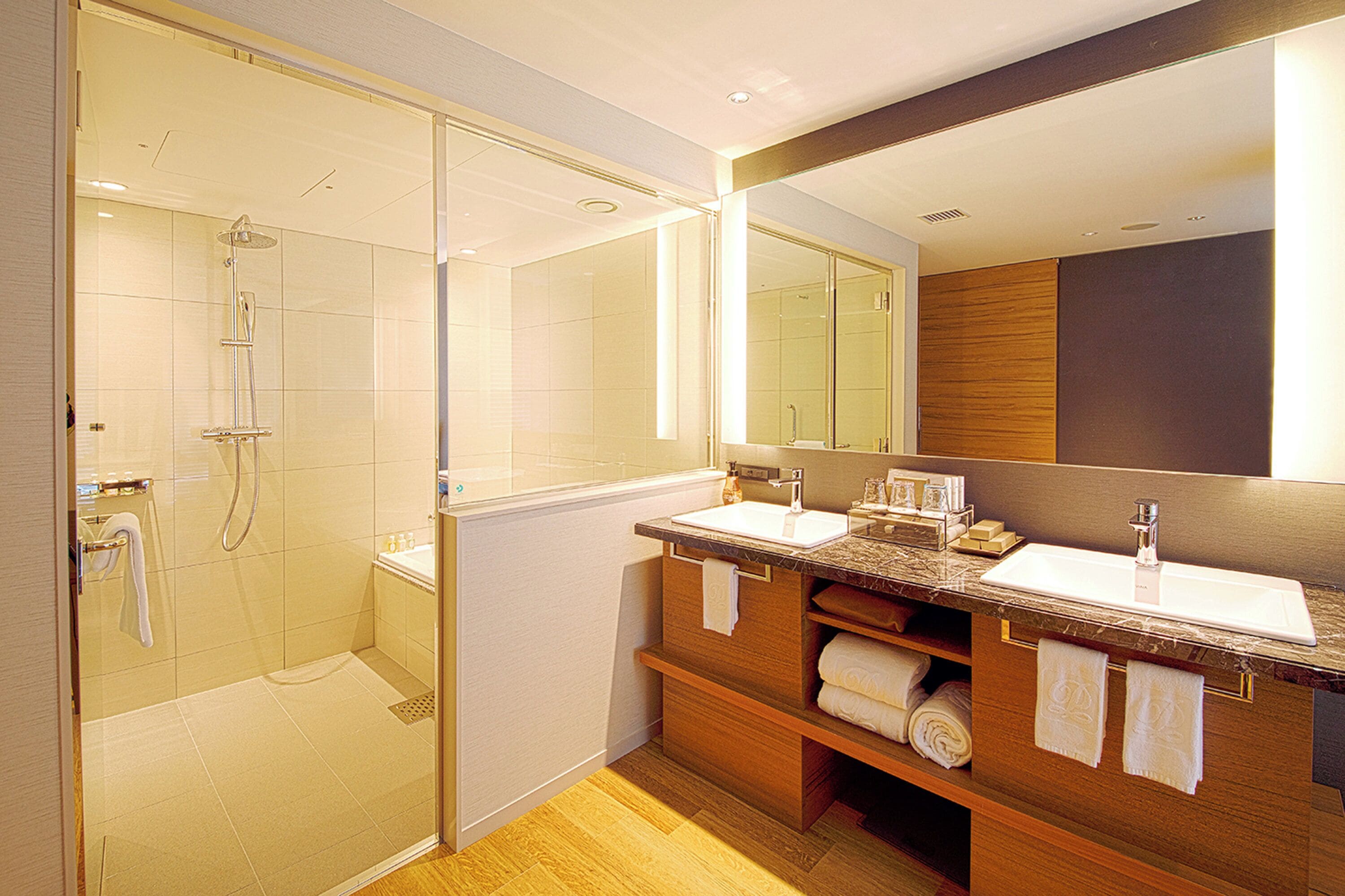 A modern bathroom with a glass-enclosed shower, dual sinks, and a large mirror.