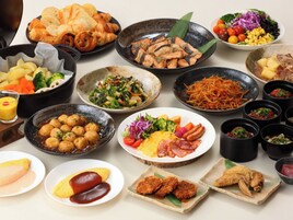A variety of dishes on a table, including sushi, salads, and meat dishes.